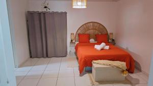 a bedroom with a bed with an orange bedspread and a pillow at Appartement Talou in Le François
