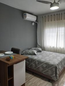 a bedroom with a bed and a desk and a window at Consulado Americano Studio 40 mts do Consulado do Estados Unidos in Porto Alegre