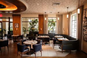 a restaurant with tables and chairs and windows at Kimpton La Peer West Hollywood by IHG in Los Angeles
