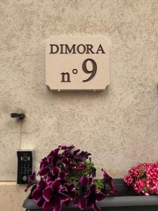 a sign on the side of a wall with purple flowers at Dimora n 9 in Locorotondo