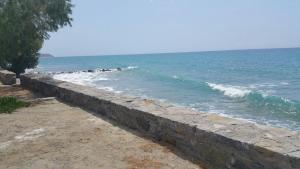 a stone retaining wall next to the ocean at Xenos Apartments in Keratokampos