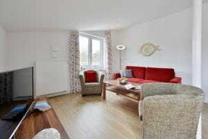 ユリウスルーにあるFerienwohnung Strandkorbのリビングルーム(赤いソファ、椅子付)