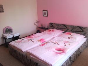 ein Bett mit rosa Blumen darauf in einem Schlafzimmer in der Unterkunft Tannhäuser b&b in Bad Dürrheim