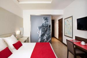 a bedroom with a bed and a desk with a red blanket at Grupotel Gran Via 678 in Barcelona