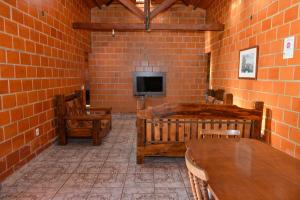 a room with a brick wall with a tv and tables at CHACARA HORTOLAN in Mairinque