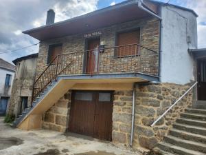 a brick house with a wooden door and stairs at Casa rural in Ourense