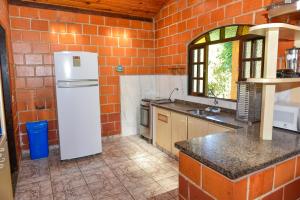 a kitchen with a white refrigerator and a brick wall at CHACARA HORTOLAN in Mairinque