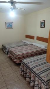 two beds are lined up in a room at Hotel Perseo Inn in Barranca