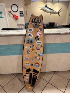 a surfboard with stickers on a counter in a kitchen at Hole Inn the Wall Hotel - Fort Walton Beach - Sunset Plaza - nearby Beaches & Hurlburt in Fort Walton Beach