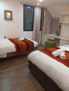 a hotel room with two beds and a chair at Departamento con súper desayuno in Cusco +66 photos