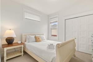 a white bedroom with a bed and a table with a lamp at The Willow - 20 Butternut in Cherry Valley