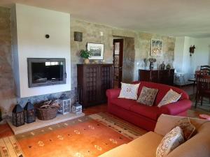 ein Wohnzimmer mit einem roten Sofa und einem Fernseher in der Unterkunft Casa dos Limões - Paredes de Coura in Formariz