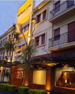 a building with palm trees in front of it at HOTEL CASTELAR CORDOBA in Córdoba