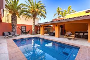 une piscine devant une maison avec des palmiers dans l'établissement La Posada Alberca privada y playa cercana, à La Paz