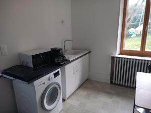 a kitchen with a washing machine and a microwave at Laura Happy Guest House in Tenay