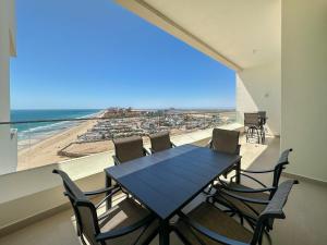 a dining room with a table and chairs on a balcony at 2BR Sandy Beach Beachfront Getaway in Puerto Peñasco