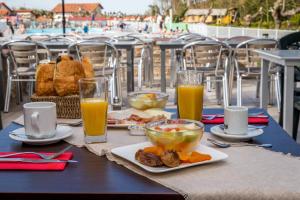 einen Tisch mit Speisen und Gläsern Orangensaft in der Unterkunft Hôtel Prestige Odalys Erromardie in Saint-Jean-de-Luz