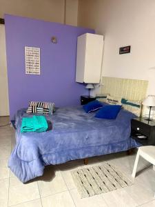 ein lila Schlafzimmer mit einem großen Bett mit blauen Laken in der Unterkunft Monoambiente EK Centro Neuquén in Neuquén