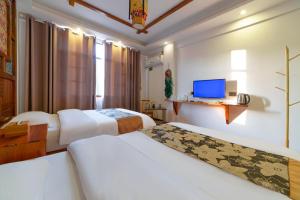 Una habitación de hotel con dos camas y un televisor. en Zhangjiajie Xinghe Qingmeng Inn offers free shuttle service to the vicinity of the east gate of the National Forest Park, advance purchase of scenic spot tickets, free laundry service, and freshly ground coffee, en Zhangjiajie