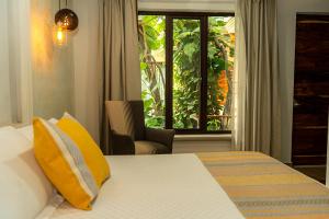 a bedroom with a bed with yellow pillows and a window at Hotel Casa Vertiz in Oaxaca City