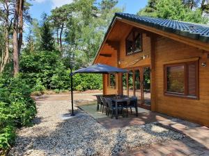 a table with an umbrella in front of a house at Villa in Forest with Private Sauna in Markelo