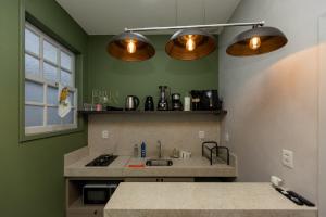 a kitchen with green walls and a sink and lights at Casa Festival - Caminhos de OP in Ouro Preto
