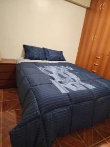 ein Schlafzimmer mit einem Bett mit einer blauen Bettdecke in der Unterkunft Departamento en la Soledad-Huaraz in Huaraz