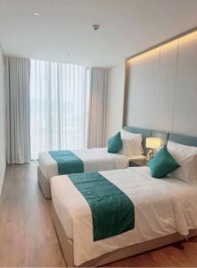 Una habitación de hotel con dos camas y una gran ventana. en Đặt phòng chính chủ Hạ Long Lh, en Ha Long