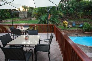 un patio con tavoli e ombrelloni accanto alla piscina di Woodlands Guest House a Hazyview
