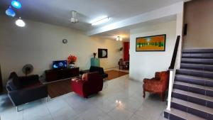 a living room with couches and chairs and a staircase at Homestay Ipoh Maziah in Ipoh