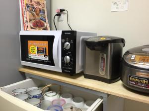 a microwave sitting on a shelf next to a coffee maker at Kyoto Guesthouse Oyado Kei in Kyoto +15 photos