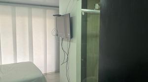 1 dormitorio con TV en la pared junto a una cama en Apartaestudio6 sector Cable Estadio, en Manizales
