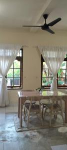 Un comedor con una mesa y dos ventanas. en Rumah Sedana, en Ubud