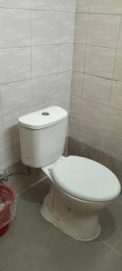 Un inodoro blanco sentado en un baño junto a una pared en Rumah Sedana, en Ubud 3 fotos más