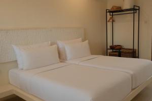 a white bed with white pillows in a room at El Tropico Boutique Hotel in Kuta Lombok