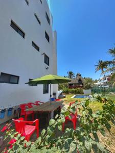 a table with a green umbrella next to a building at Apolo Apartment, near the beach with pool in Barra de Navidad