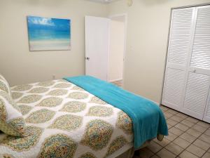 a bedroom with a bed with a blue blanket on it at Sand Dollar Beach Side Villa in Holmes Beach