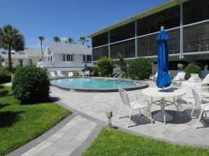 a pool with chairs and a table and a blue umbrella at Sunset Beach 101 Beach Front Unit in Holmes Beach