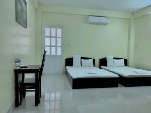 a bedroom with two beds and a table and a chair at Thinh Khang Hotel Vung Tau in Vung Tau +67 photos