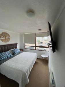 Un dormitorio con una cama y un televisor de pantalla plana. en Jardín Del Mar - Casino-Playa, en Coquimbo