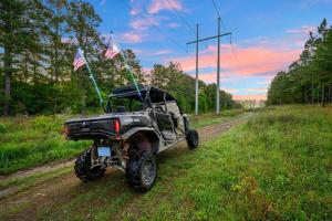 a four wheeler parked on a dirt road with flags at The Animal Crossing -Direct ATV trail access, hot tub, and fire pit near Hochatown in Broken Bow