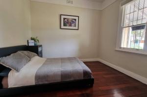 a bedroom with a bed and two windows in it at Globe Trotters Homestay - room in shared private residence in Perth +9 photos