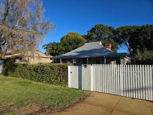 a white fence in front of a house with a roof at Globe Trotters Homestay - room in shared private residence in Perth