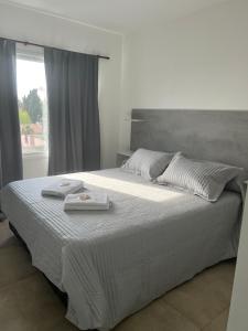 a white bed with two towels on top of it at Departamento Rivadavia in Olavarría