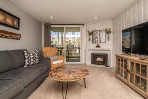 a living room with a couch and a table and a television at Walk to the Beach Sunset Ocean Views - D-207 in Oceanside