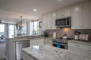 a kitchen with white cabinets and granite counter tops at Panoramic Water Views - Steps to the Beach - F-2 in Oceanside +56 photos