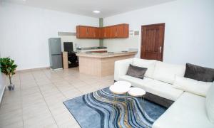 a living room with a white couch and a kitchen at Appartement Moderne & Confortable Proche Aéroport Léon-Mba, Libreville in Libreville