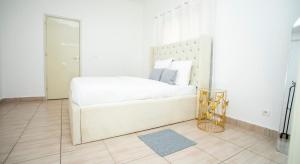 a white bedroom with a white bed and a mirror at Appartement Moderne & Confortable Proche Aéroport Léon-Mba, Libreville in Libreville