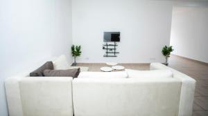 a white living room with a white couch and a tv at Appartement Moderne & Confortable Proche Aéroport Léon-Mba, Libreville in Libreville