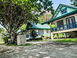 a blue and white house with a tree in front of it at ZHANG RESORT and DIVE CENTER in Daanbantayan